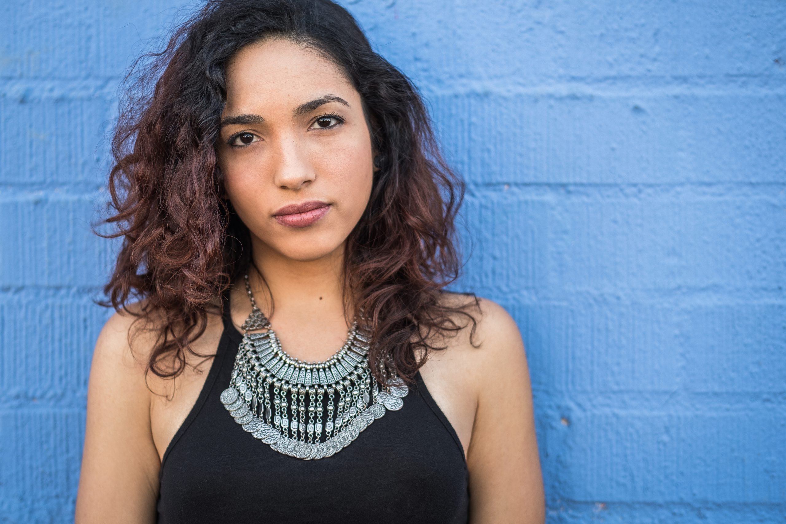 picture of a young woman in front of a blue cement wall.