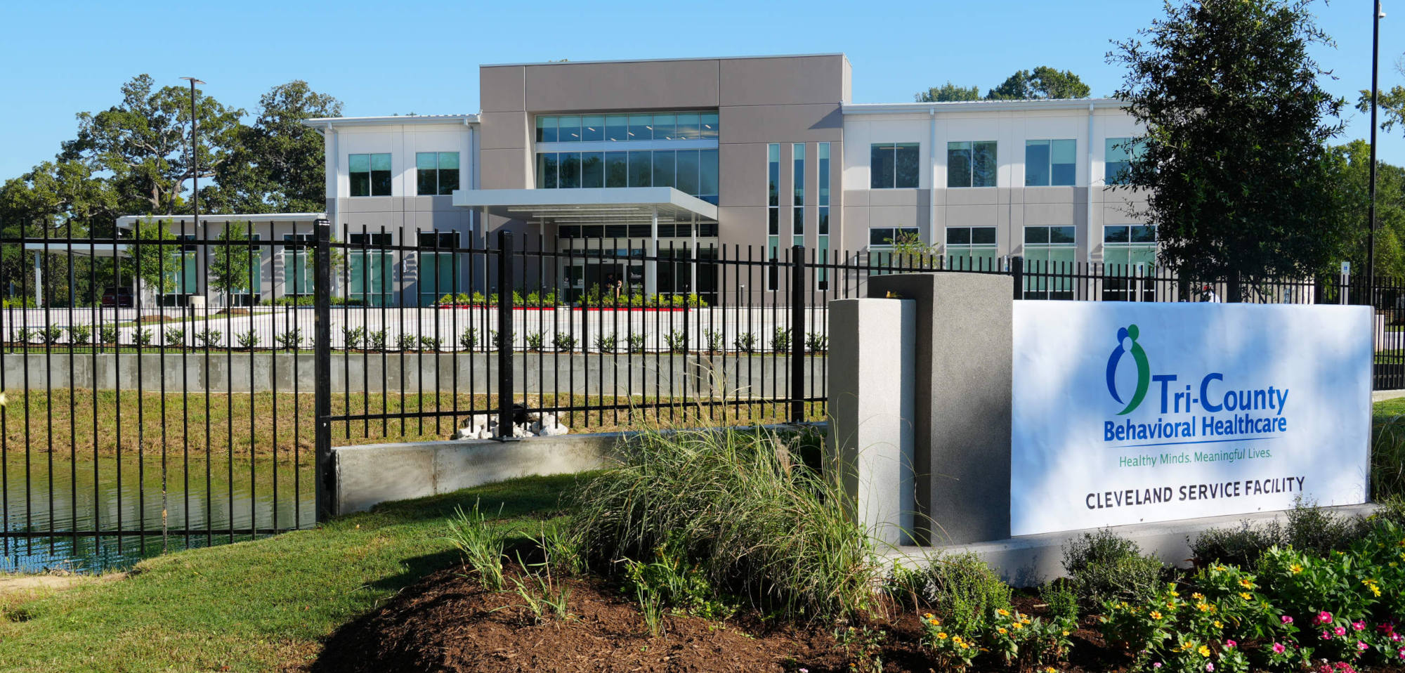 Picture of the front of the Tri County Behavioral Healthcare Cleveland Service facility. Services include Initial Evaluation and Intake, Psychiatric Evaluation, Medication Management, Nursing, Therapy, Skills Training, Wraparound Case Management, Family Partner Services, IDD Day Programming and IDD Testing, and Outpatient Youth and Adult Substance Use Disorder Services. The new service location is at 402 Liberty Street, Cleveland Texas 77327.